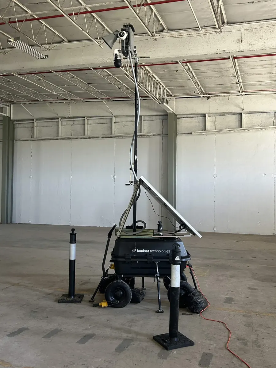 LOBO in an empty warehouse bay, with an orange extension cord running to its equipment box.