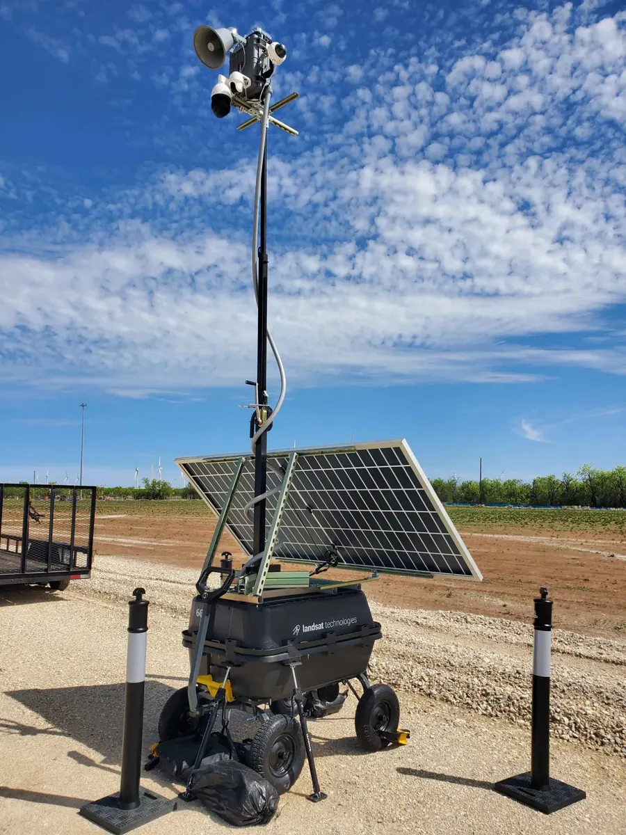 LOBO on a gravel laydown yard under a blue sky, with wind turbines on the horizon.