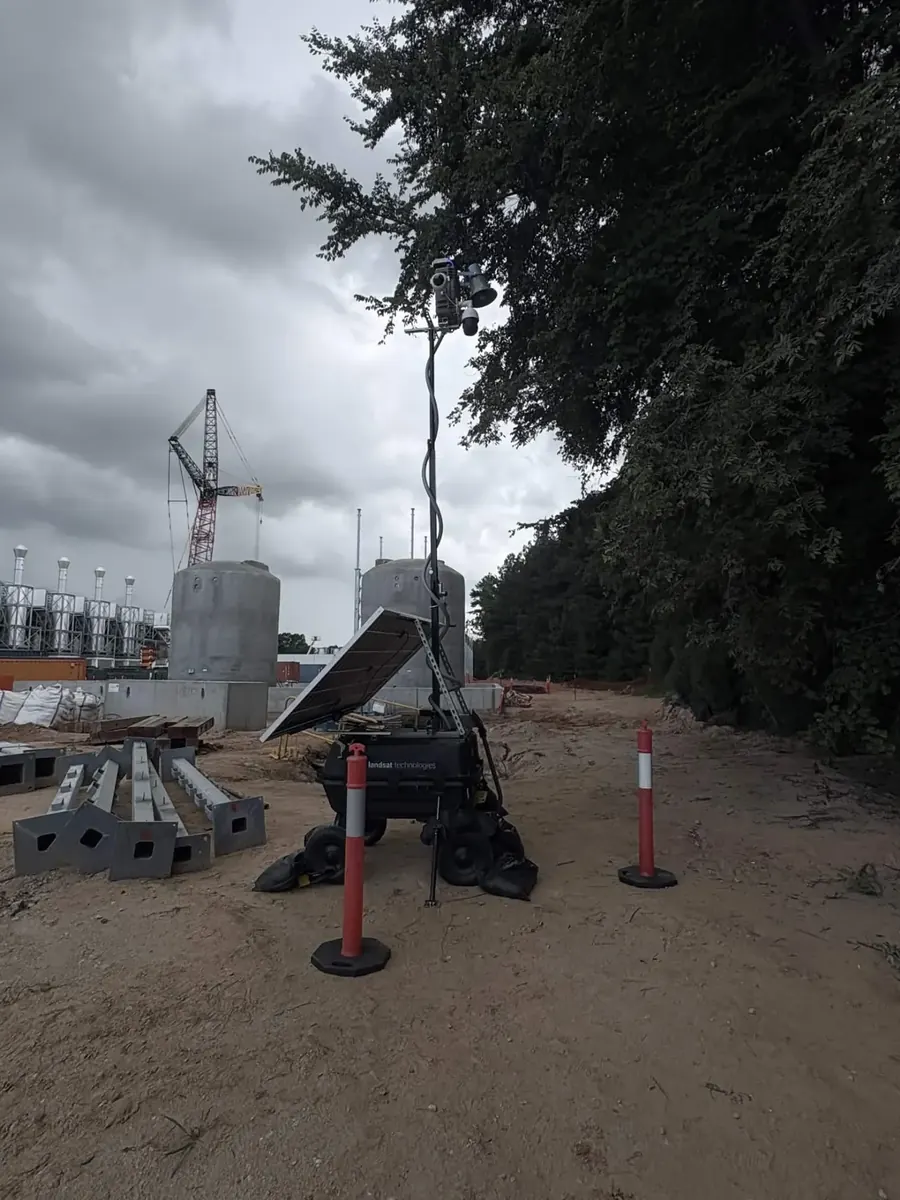 LOBO under a stormy sky on a power plant construction site, with generator stacks, tanks and a crane behind.