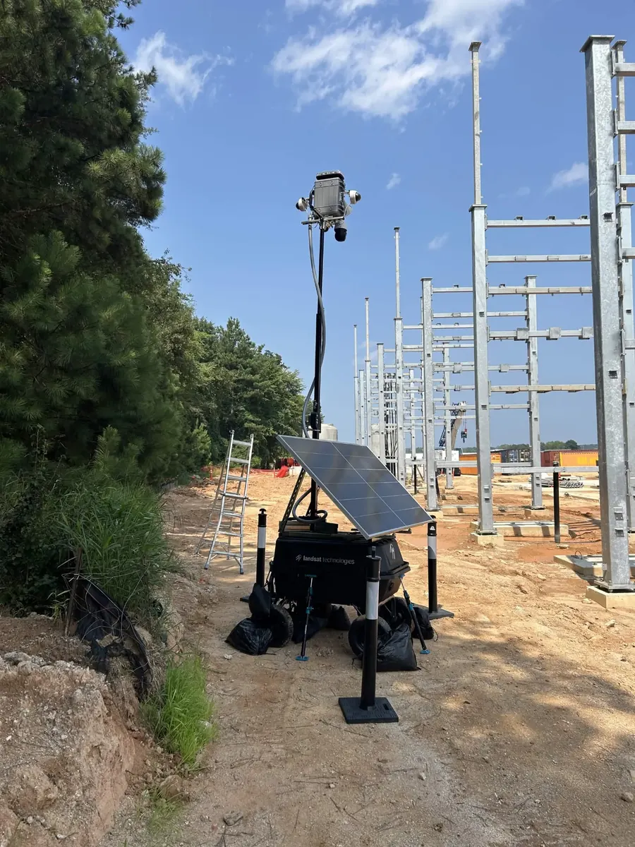 LOBO beside rows of new steel electrical structures, against a tree line.