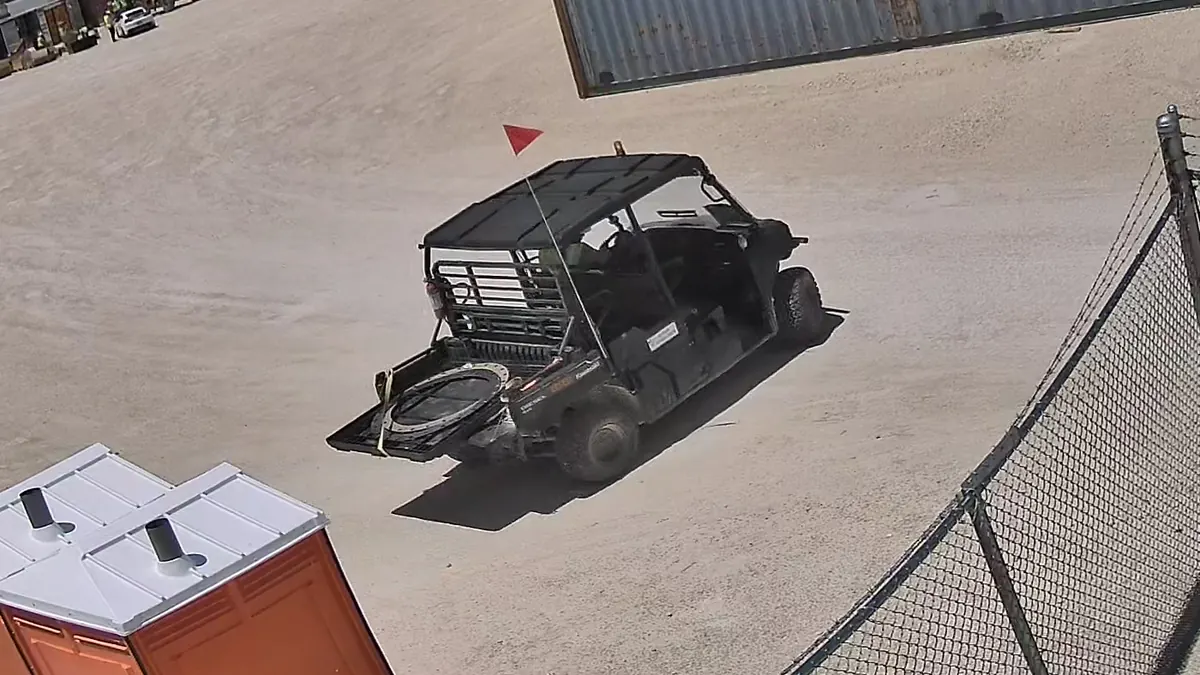 Tower camera: a work cart crossing an equipment yard with large ring gaskets in its bed.