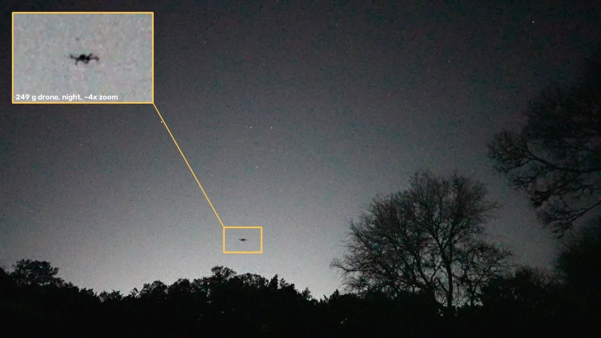 Night sky over a treeline with a tiny drone boxed in amber; an inset enlarges it, labeled 249 g drone, night, about 4x zoom.